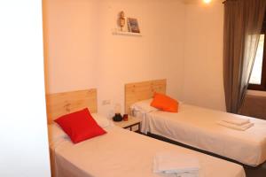 バルデリナレスにあるEl Refugio Valdelinares Gastro Hostalの赤い枕付きのベッド2台が備わる客室です。