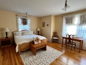 a bedroom with a bed and a desk and windows at Stirling House in Kelowna