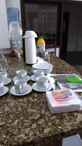a counter with white plates and cups and cups at CASA ACONCHEGANTE PROXIMO VILA GERMÂNICA in Blumenau