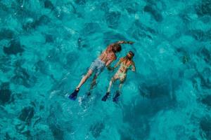 two women are swimming in the blue water at All Inclusive Luxury Yacht with Private Island in Cancún