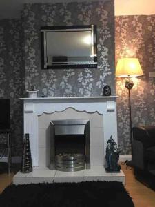 a living room with a fireplace with a mirror at 31 end terrace in Whitehead
