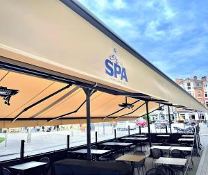 a group of tables and chairs under a large umbrella at Hôtel-Restaurant L'Auberge in Spa