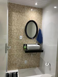 a bathroom with a sink and a mirror on a wall at Casa em Arraial do Cabo na praia grande in Arraial do Cabo