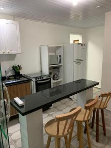 a kitchen with a counter with chairs and a refrigerator at Casa em Arraial do Cabo na praia grande in Arraial do Cabo