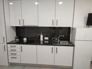 a kitchen with white cabinets and a sink at Penedo Grande suítes Estúdio in São Bartolomeu de Messines +1 photo