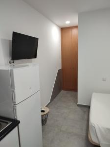 a room with a tv on top of a refrigerator at Penedo Grande suítes Estúdio in São Bartolomeu de Messines