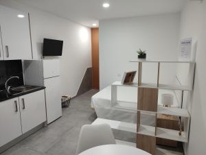 a kitchen with white cabinets and a table and chairs at Penedo Grande suítes Estúdio in São Bartolomeu de Messines
