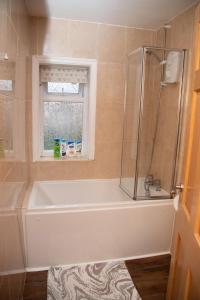 a bathroom with a bath tub and a window at Guest house in Wythenshawe