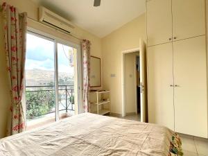 1 dormitorio con cama y ventana grande en Quiet cozy cool apartment with full new AC and fast Wi-Fi, en Peyia