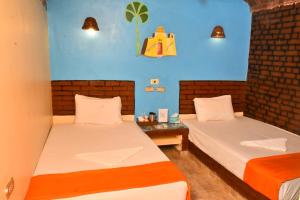 two beds in a room with blue walls at Kulih Nubian House in Shellal