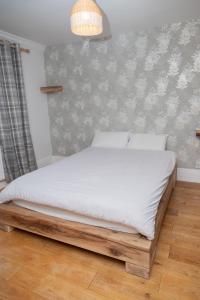 a bedroom with a bed with white sheets and a wall at Guest house in Wythenshawe