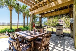 a wooden table and chairs under a wooden pergola at Grand Pointe Unit 506 in Orange Beach