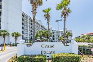 a sign in front of a building with palm trees at Grand Pointe Unit 506 in Orange Beach
