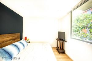 ein Schlafzimmer mit einem Bett und einem großen Fenster in der Unterkunft Sophisticated Park Venue Apartment Near Polanco - Nadal 101 in Mexiko-Stadt