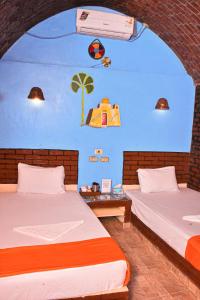 two beds in a room with a wall with a mural at Kulih Nubian House in Shellal