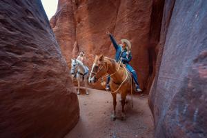 a woman riding a horse in a slot canyon at Zion Ponderosa Ranch Resort in Springdale