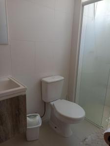 a white bathroom with a toilet and a shower at Praia de Palmas in Governador Celso Ramos