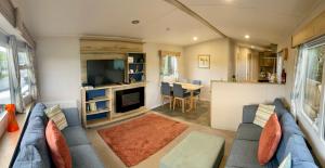 a living room with a blue couch and a tv at Appleblossom Lodge, Lido Leisure Park, Knaresborough in Knaresborough
