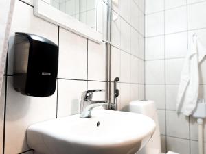 a bathroom with a sink and a soap dispenser on the wall at Cozy city suites in Rovaniemi +1 photo