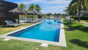 a swimming pool with chairs and umbrellas in a yard at Condomínio de Luxo Praia do Forte - Iberostate - refugio de paz in Praia do Forte