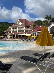 a pool with chairs and an umbrella and a hotel at Karibbean Resort in Sainte-Luce