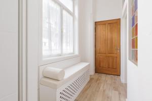 a white bathroom with a window and a wooden door at Cozy & 3 minutes from main square - J in Zagreb