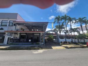 a building with palm trees in front of a street at Wide Mouth Frog Quepos in Quepos