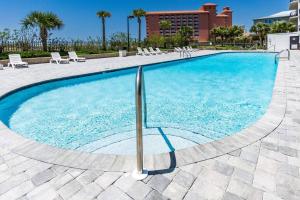 Una gran piscina con sillas y un edificio. en Grand Pointe Unit 404, en Orange Beach