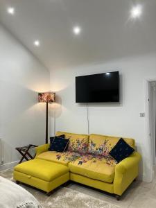 um sofá amarelo numa sala de estar com uma televisão de ecrã plano em The Maisonette - Cultural Quarter - with parking! em Lincolnshire