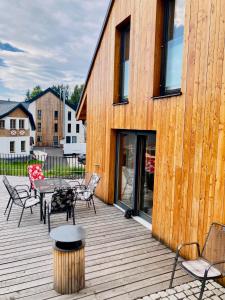 una terraza de madera con sillas, mesa y un edificio en Harrachov 702, en Harrachov