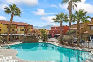 a swimming pool at a resort with palm trees and buildings at Mesquite Retreat 2 Bd Condo by Cool Properties LLC in Mesquite