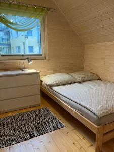 Łóżko w drewnianym pokoju z oknem w obiekcie Domki Słoneczka w Sarbinowie