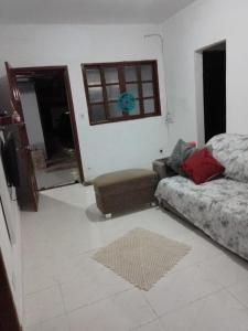 uma sala de estar com uma cama, um sofá e uma janela em Casa para temporada no Guarujá