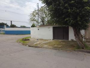a small white building with a tree next to a street at Casa para temporada in Guarujá