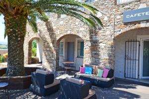 a patio with couches and a palm tree in front of a building at Hôtel la Palma in Patrimonio