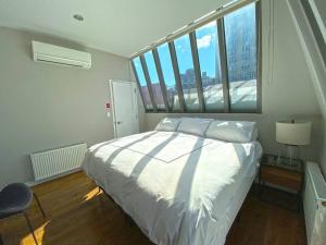 ein Schlafzimmer mit einem Bett und einem großen Fenster in der Unterkunft Gorgeous Three Bedroom West Village Townhouse in New York