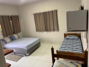 a bedroom with two beds and a flat screen tv at POUSADA ORTEGA in Bodoquena