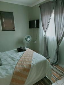 1 dormitorio con 1 cama y ventana con ventilador en Gentle Breeze, en Burgersfort