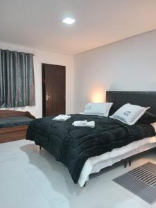a bedroom with a large bed with a black blanket at Estalagem Floradas da Serra in São Joaquim