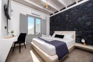 Ambiente Luxury Suites في إيوس خورا: غرفة نوم بسرير وجدار صخري