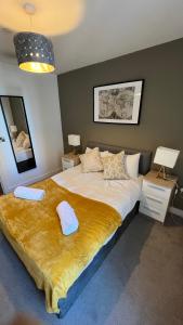Stunning Manchester City Centre Apartment! Ideal for small groups في مانشستر: غرفة نوم بسرير كبير مع بطانية صفراء