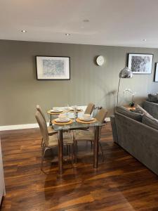 Stunning Manchester City Centre Apartment! Ideal for small groups في مانشستر: غرفة طعام مع طاولة وكراسي وأريكة