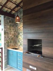 een keuken met een stenen muur en een open haard bij Apartamento Reserva Imbassaí quarto e sala 68m² in Mata de Sao Joao