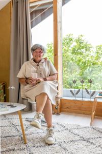 una mujer mayor sentada en una silla en una habitación con ventana en Vakantiewoning StroEnzo, en Riemst
