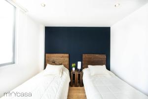 Duas camas num quarto com uma parede azul em Bright Stylish Apartment Near Polanco em Cidade do México