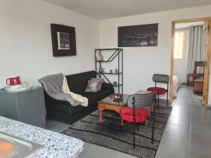 sala de estar con sofá negro y sillas en le cosy, en Fez