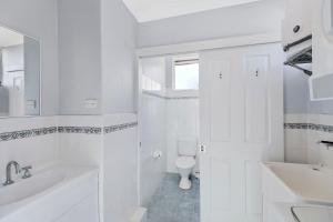 a white bathroom with a toilet and a sink at Golden Sands Apartment 10 in The Entrance