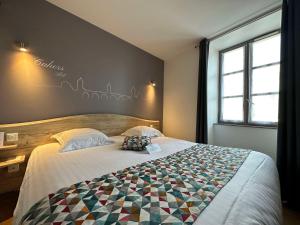 Un dormitorio con una cama con una colcha encima en Best Western Le Pont d'Or, en Figeac