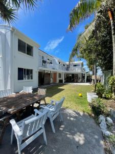 a backyard with a wooden table and chairs and a house at CALI Backpackers in Caloundra