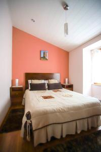 1 dormitorio con 1 cama grande y pared de color naranja en 2 bedrooms house with city view shared pool and enclosed garden at Sortelha, en Sortelha